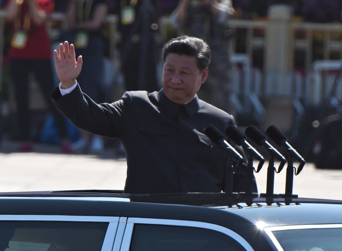 Chinese President Xi Jinping waves as he reviews troops from a car during a military parade at Tiananmen Square in Beijing.