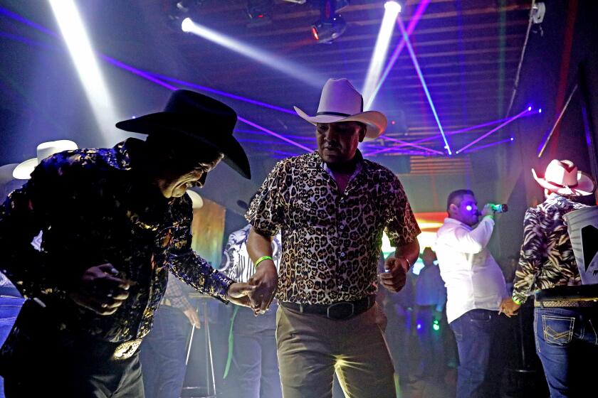 ZACATECAS, ZACATECAS - APRIL 06: Daniel Renteria, 56, left, of Zacatecas, dances with another cowboy at the welcoming party at Juana VIP Club Mix in the historic center on Thursday, April 6, 2023 in Zacatecas, Zacatecas. Rentiria attended the reunion with his partner Ramiro Garcia, 36, who he lives with in Zacatecas. Each spring, hundreds of men gather in Zacatecas, Zacatecas for an annual gay cowboy convention "Reunion Vaquera." They come from around the country and don Stetsons, tight jeans and boots to flirt and dance and crown a Cowboy King. (Gary Coronado / Los Angeles Times)