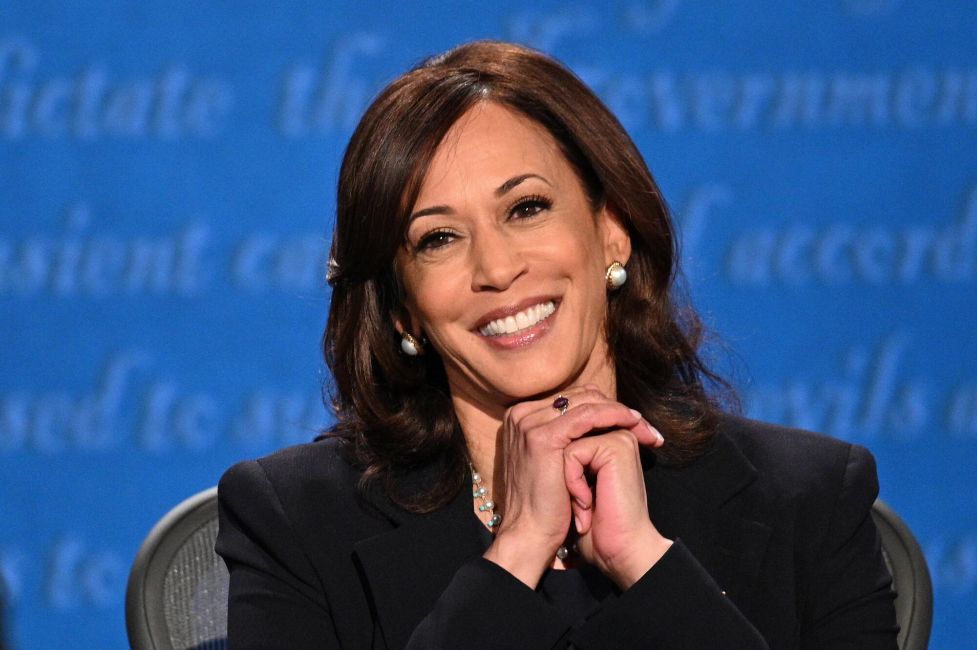 Kamala Harris smiles with her hands clasped under her chin