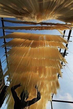 A worker hangs strands of vermicelli to dry at a factory. Vermicelli is in demand among Muslims when they break the daylong fast during the holy month of Ramadan.