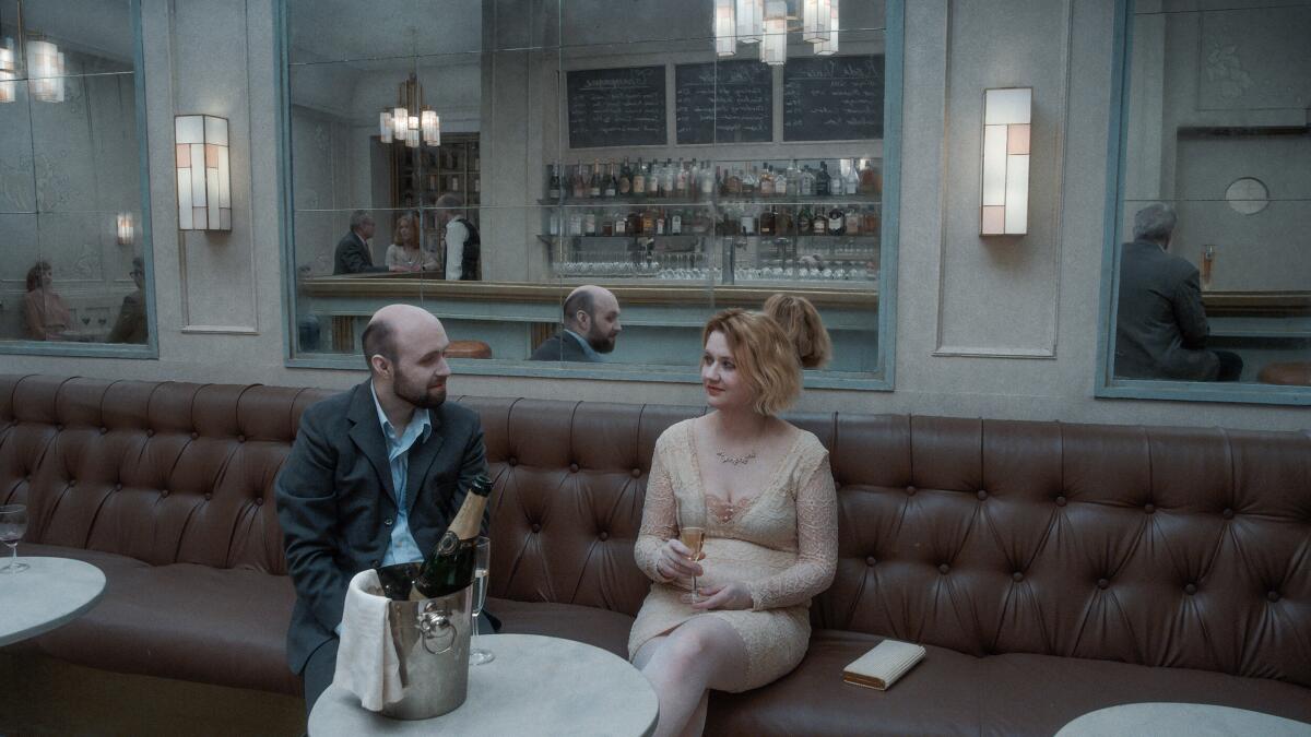 A man and woman sit on a banquette