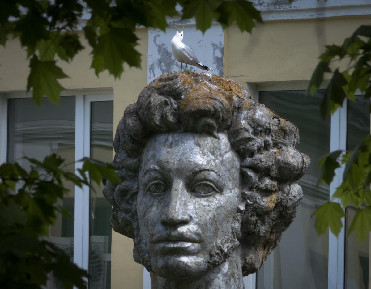 A bird sits on the head of a sculpture 