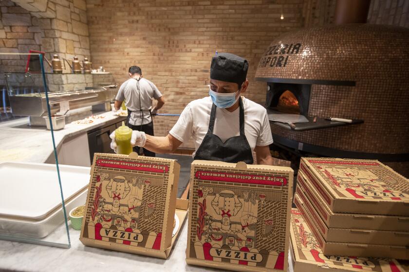 Valentine Memeron, an employee at Sapori Ristorante, prepares several pizzas for takeout on Friday, April 10.