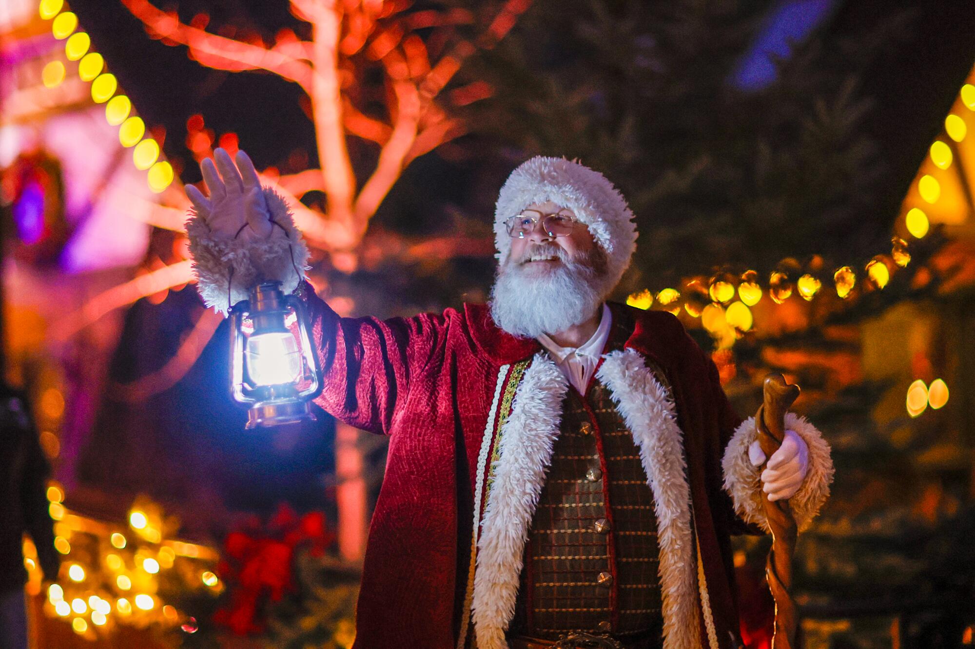 Santa Claus makes his way through Santa's Village by the light of a lantern to oversee a Christmas tree lighting ceremony.
