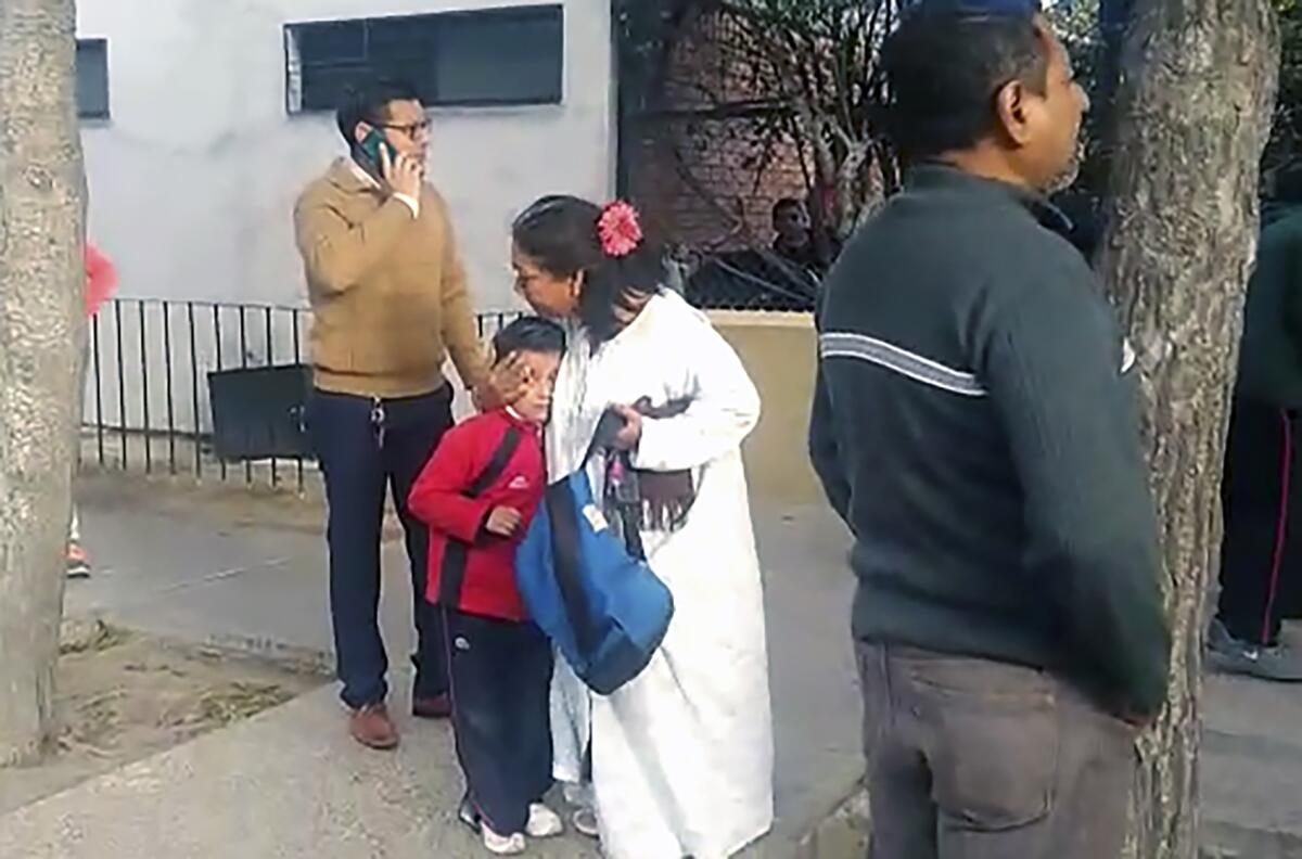 Relatives of schoolchildren gather outside the elementary school where a student shot and killed a teacher and wounded six other people, and then apparently killed himself, in Torreon, Mexico on Friday.