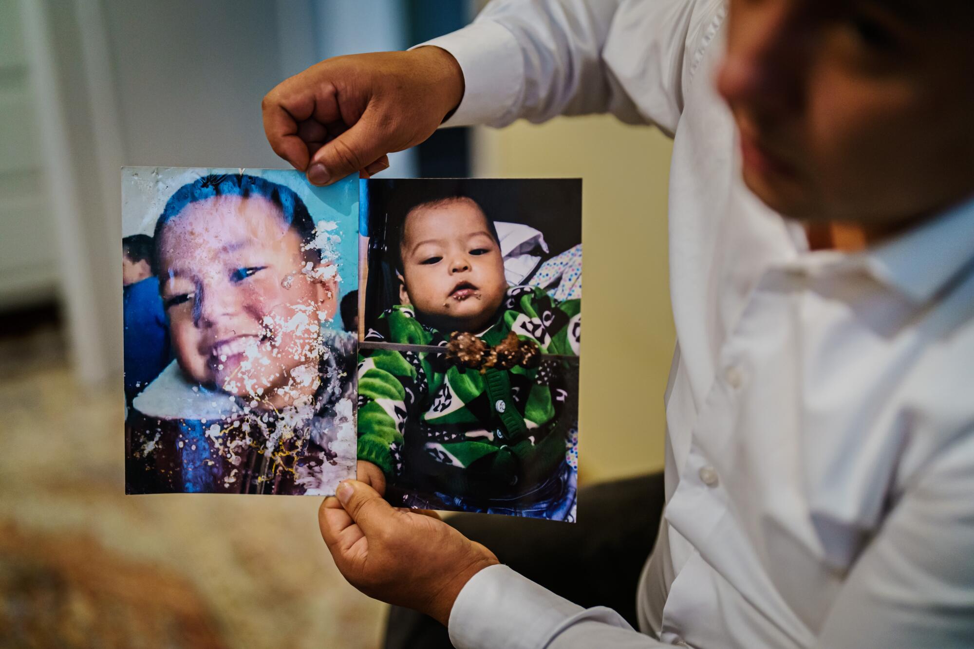 A man holds up two photos of a boy 