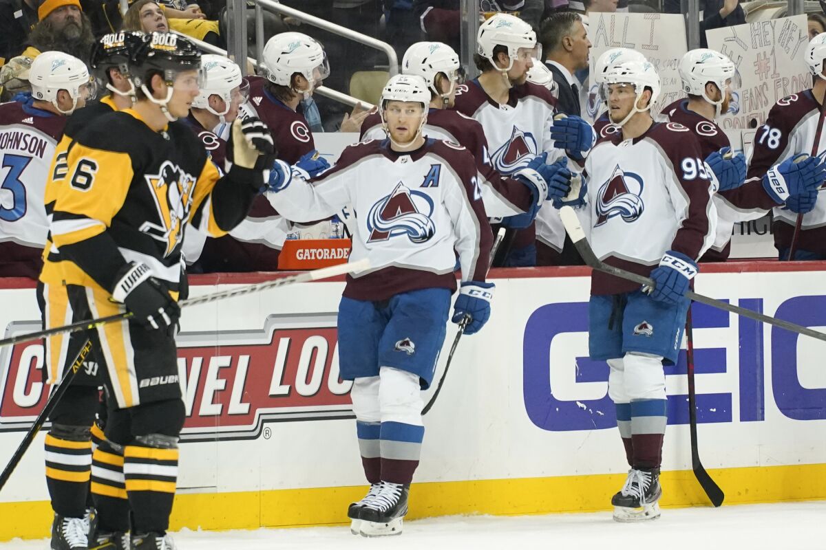 Colorado Avalanche's Nathan MacKinnon, center, celebrates with teammates on the bench after scoring against the Pittsburgh Penguins during the second period of an NHL hockey game, Tuesday, April 5, 2022, in Pittsburgh. (AP Photo/Keith Srakocic)