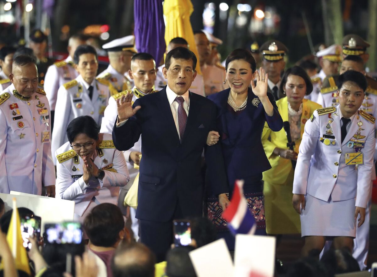 Thai King Maha Vajiralongkorn and Queen Suthida wave to supporters at the opening of a mass transit station