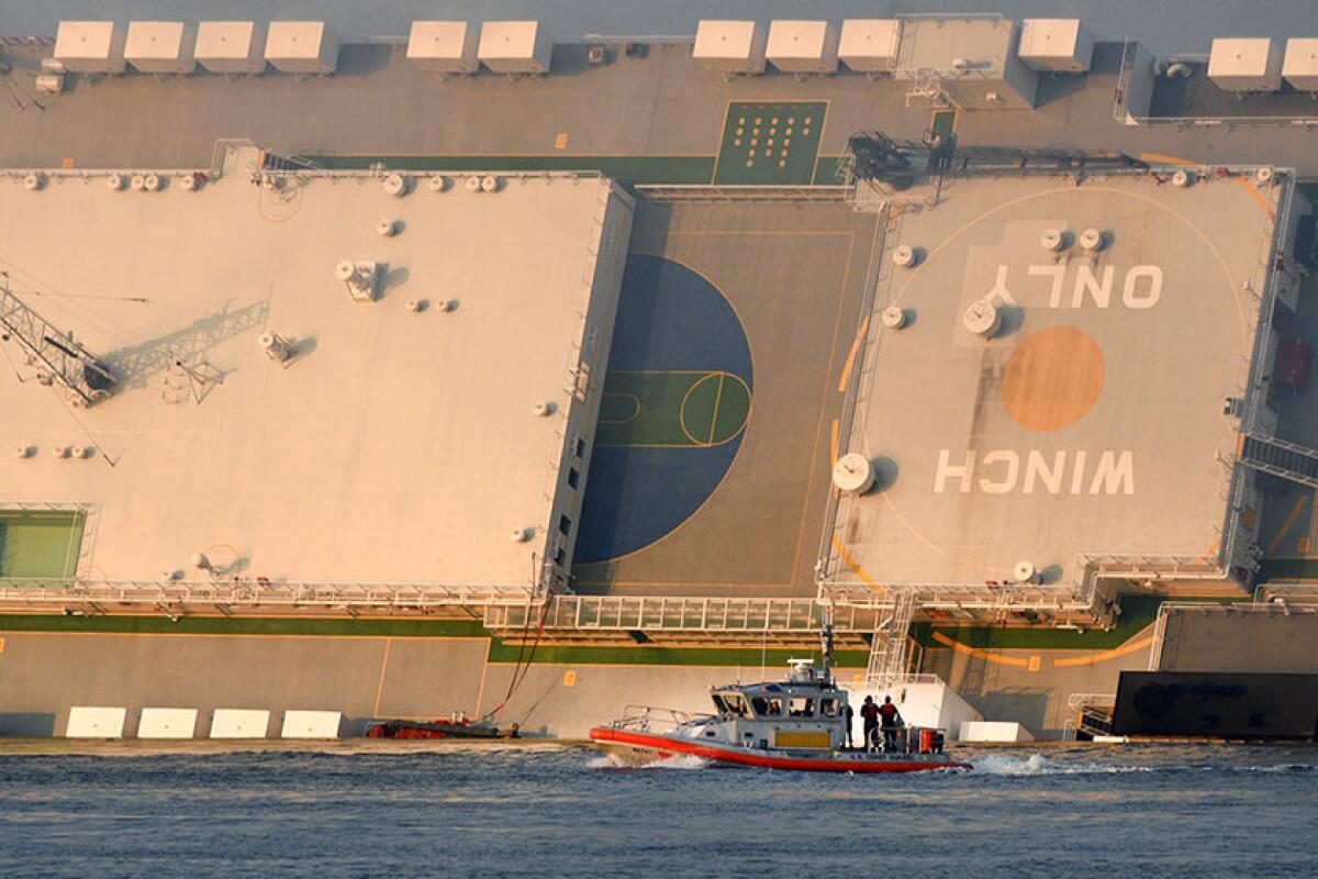 A U.S. Coast Guard boat rides in front of a cargo ship that overturned in St. Simons Sound near the Port of Brunswick in Georgia