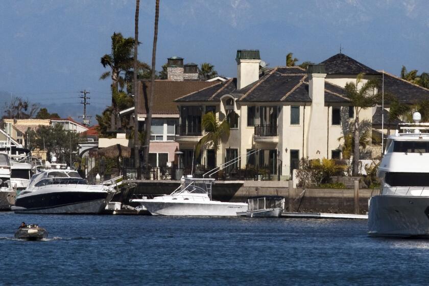 HUNTINGTON BEACH, CA. --FEBRUARY 20, 2013: A California brown pelican soars as a motor boater cruises Huntington Harbor. (Allen J. Schaben/Los Angeles Times)