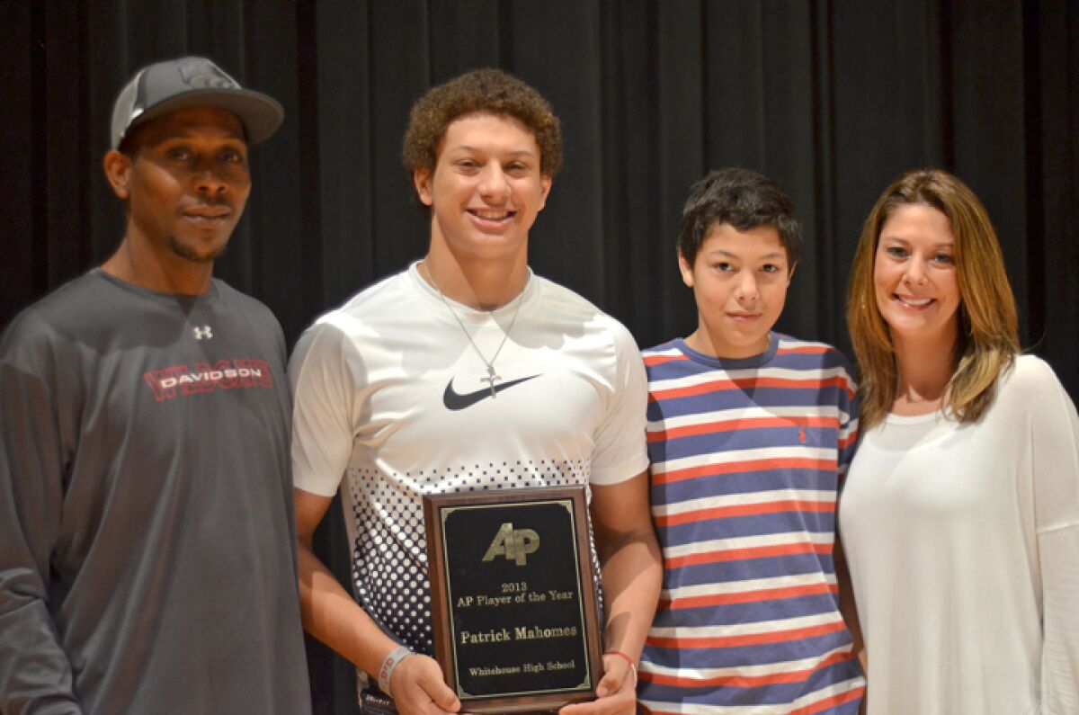 Patrick Mahomes tient son prix alors qu'il pose avec son père, Pat à gauche, son jeune frère, Jackson, et sa mère, Randi.