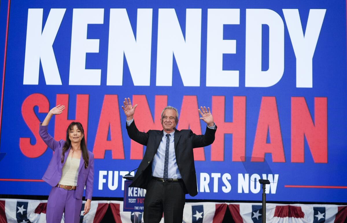 Presidential candidate Robert F. Kennedy Jr. and his running mate, Nicole Shanahan, in front of a sign bearing their names.