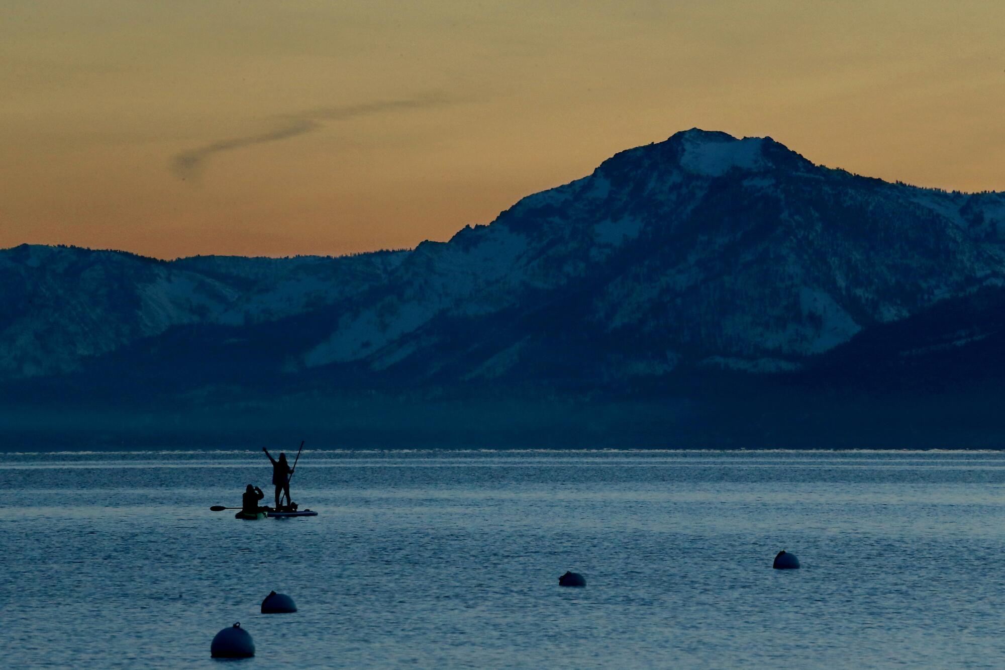 Kayakers take in the snow-covered Sierra Nevada as the sun sets on Lake Tahoe.