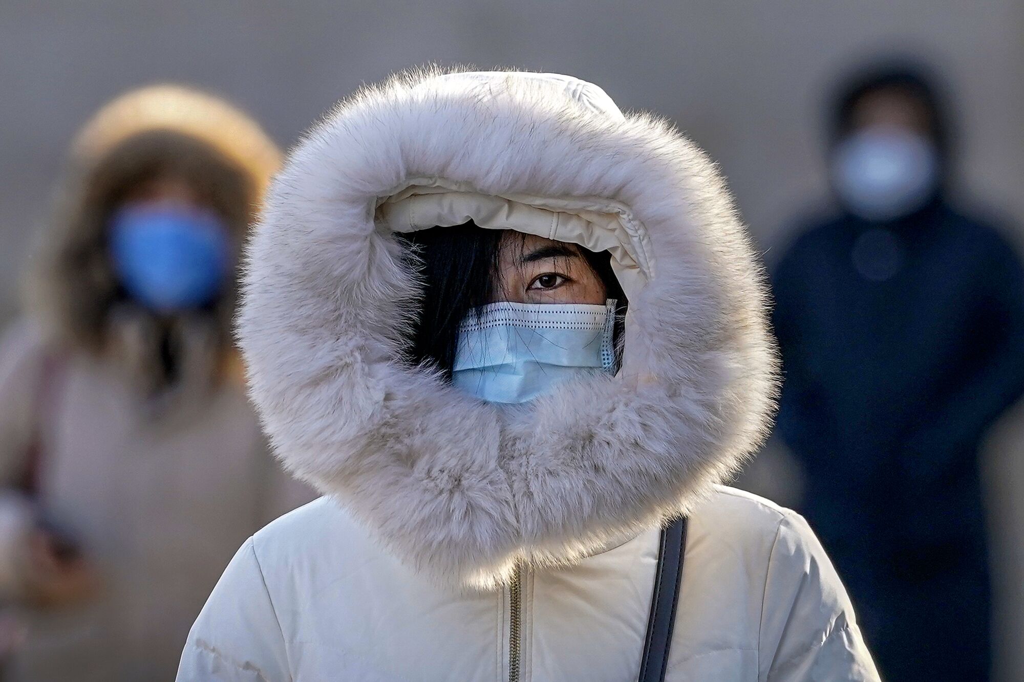 A pedestrian in Beijing relies on a mask and a hood to ward off coronavirus contagion and the chill.