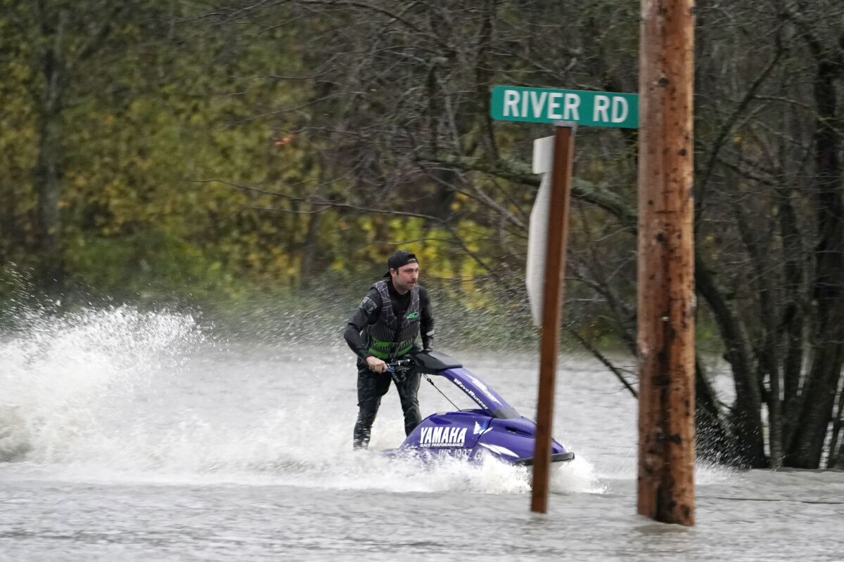 A man operates a personal watercraft along a road flooded by water from the Skagit River, Monday, Nov. 15, 2021, in Sedro-Woolley, Wash. (AP Photo/Elaine Thompson)