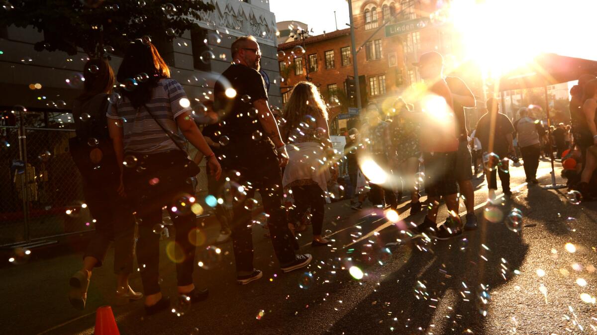 Fans walk through a sea of soap bubbles as the sun sets on the Music Tastes Good festival in Long Beach.
