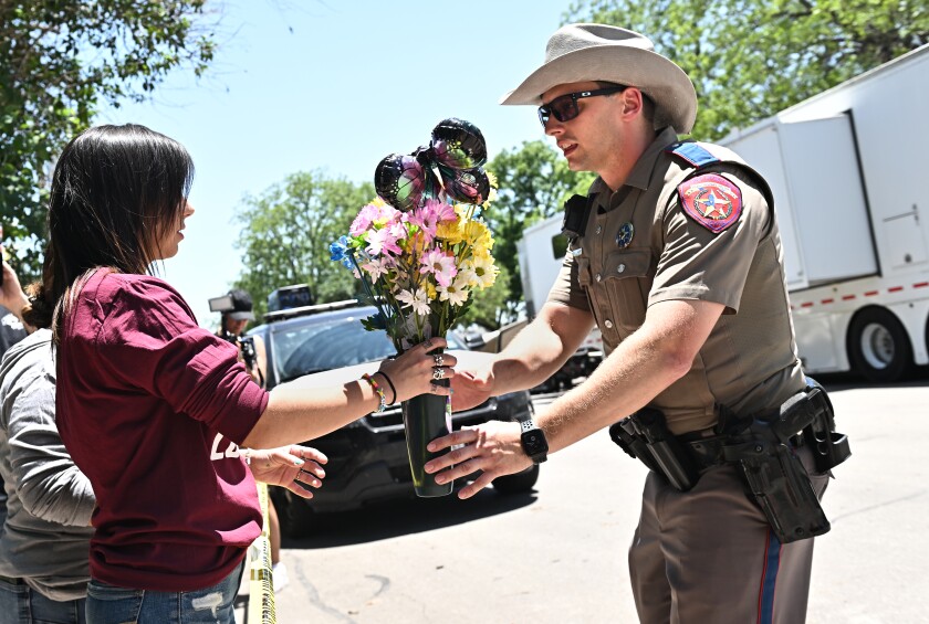 Amanda Welch gives flowers to an officer to place at a memorial outside of Robb Elementary School