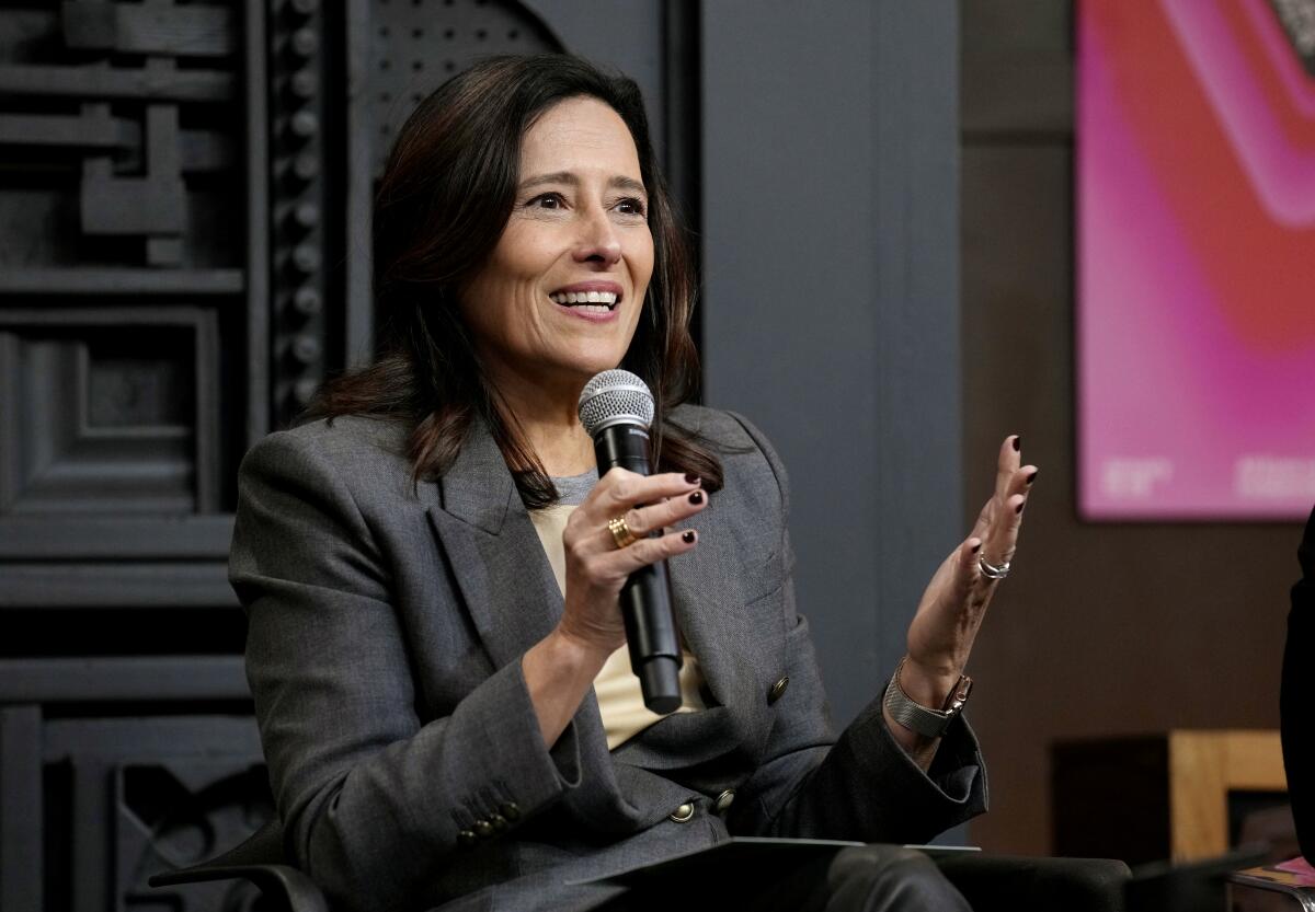 A smiling woman speaks into a microphone.