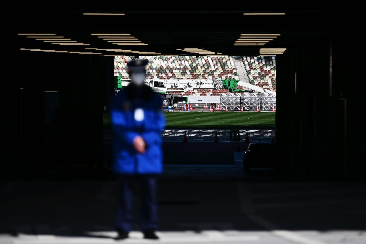 A masked security guard stands in front an entrance to National Stadium, a venue for the 2020 Tokyo Olympics.