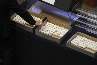 A person reaches toward balls with numbers printed on them
