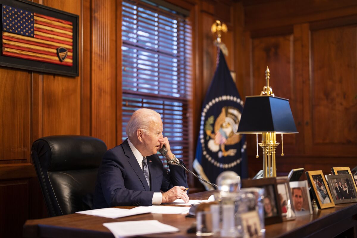 President Biden seated at a desk talking on a phone.