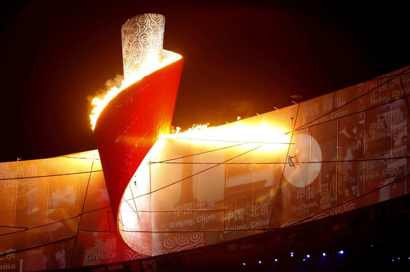 Suspended by a harness, 1984 Olympic champion gymnast Li Ning, 45, moves along the stadium's upper level to light the cauldron during the Opening Ceremony at the Beijing National Stadium for the 2008 Summer Olympics.