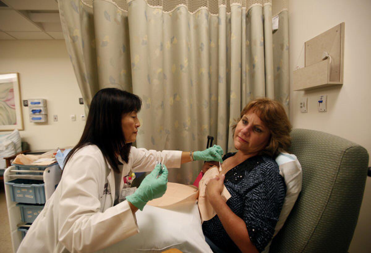 Nurse Harumi Mankarios examines Tina Roark, a patient with advanced breast cancer.