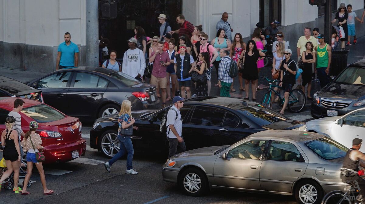 Pedestrians make their way through a maze of cars in the crosswalk at the intersection of Hollywood Boulevard and Highland Avenue, which is considered one of the worst for pedestrian collisions in Los Angeles.
