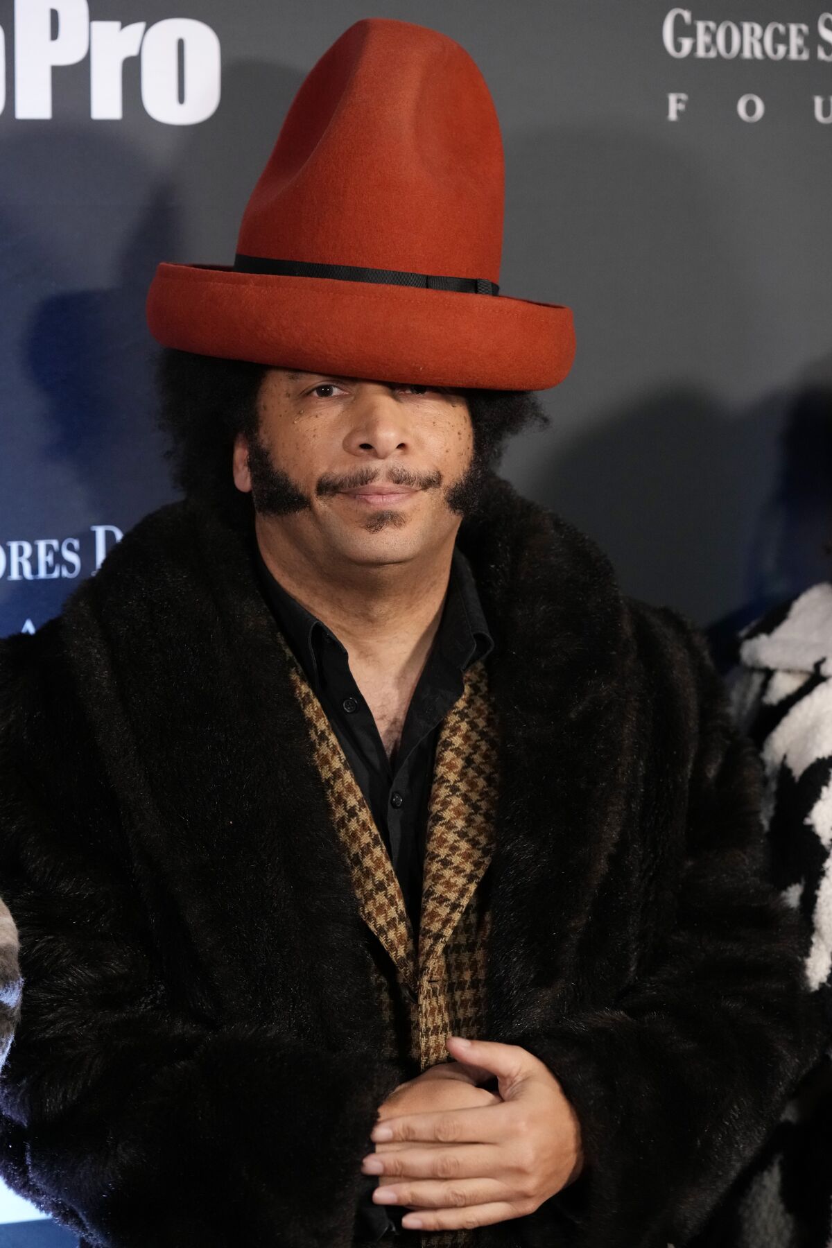 Boots Riley in a coat and large orange hat.