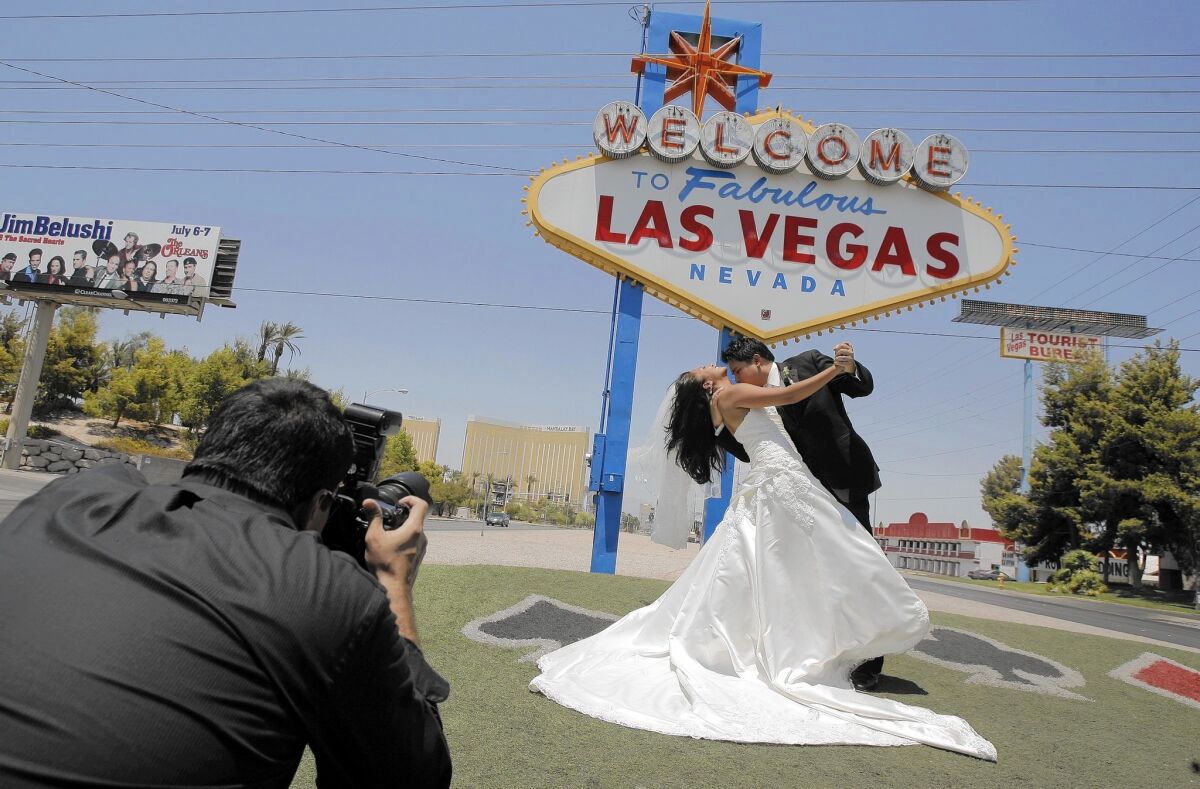 A couple get married with the "Welcome to Fabulous Las Vegas" sign in the background.