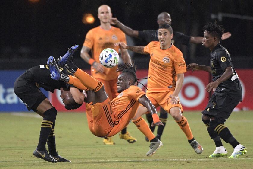 Houston Dynamo forward Alberth Elis (7) falls over Los Angeles FC midfielder Eduard Atuesta, left, while fighting for a header during the first half of an MLS soccer match, Monday, July 13, 2020, in Kissimmee, Fla. (AP Photo/Phelan M. Ebenhack)