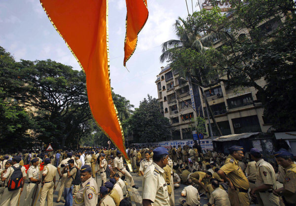 A flag of the Shiv Sena party hangs in the foreground as Indian policemen are deployed outside the residence of Hindu nationalist politician Balasaheb Thackeray in Mumbai.