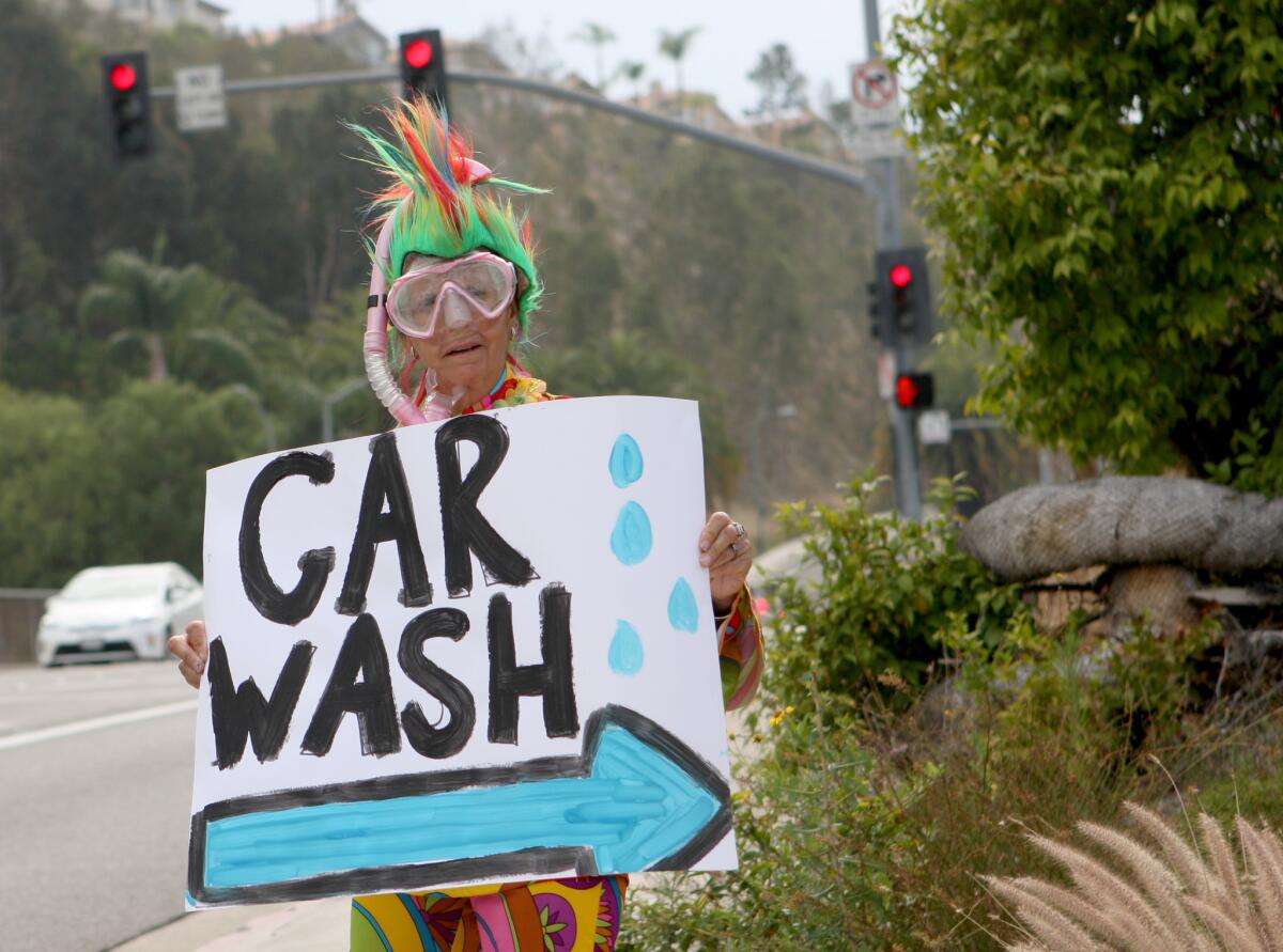 Teacher specialist Corky O'Rourke tries to attract people with her colorful outfit and hand-made sign for the 10th annual car wash fundraiser at College View School in Glendale on Tuesday, June 28, 2016.