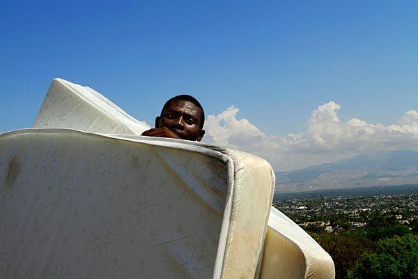 A man carries mattresses up a hill at the Petionville Club tent camp in Port-au-Prince, Haiti, as some residents are being moved to a safer camp. Petionville Club is one of the largest camps for the displaced in the capital, and engineers have identified 7,500 people to be moved immediately because of the threat of flooding. See full story
