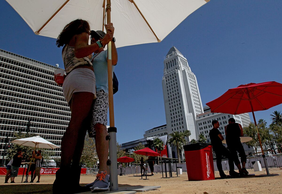 Whittier residents Robert and Heydi Cortner seek out some shade as they wait for performances to begin at the Made In America Festival in downtown Los Angeles on Sunday, Aug. 31, 2014.