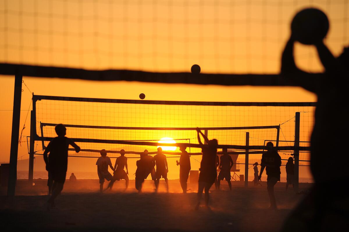 Beachgoers enjoy a game of volleyball at sunset next to the Huntington Beach Pier. California was among the top summer destinations in the 49 other states, according to a new study.