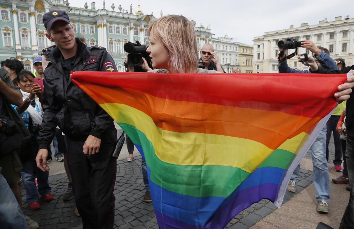 A police officer speaks with a gay rights activist standing with a rainbow flag during a protest in St. Petersburg, Russia