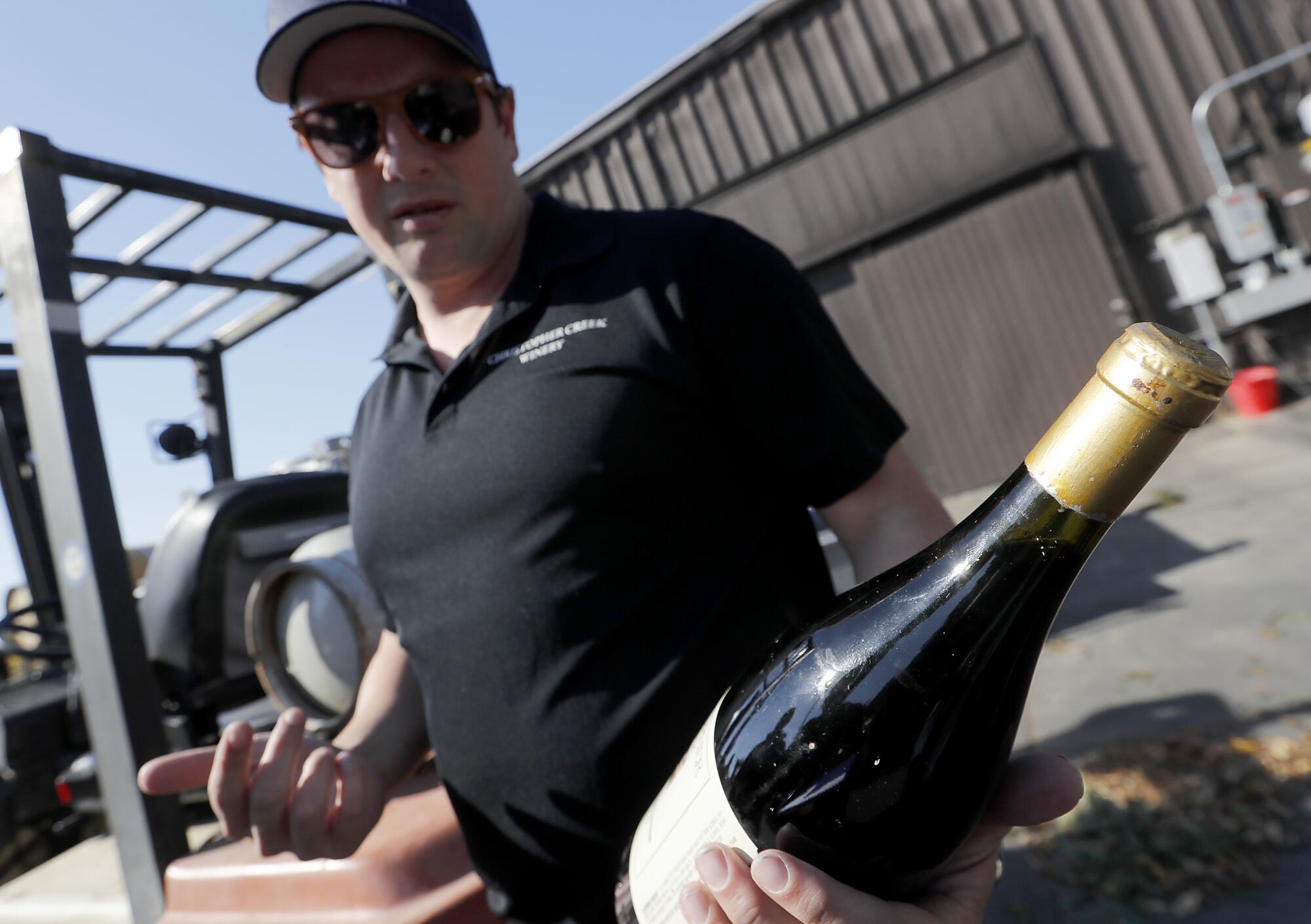 Dominic Foppoli, owner of Christopher Creek Winery and the mayor of the town of Windsor, holds a bottle of his winery's 1992 Petite Sirah that has been spoiled by the heat and smoke of the Kincade fire.