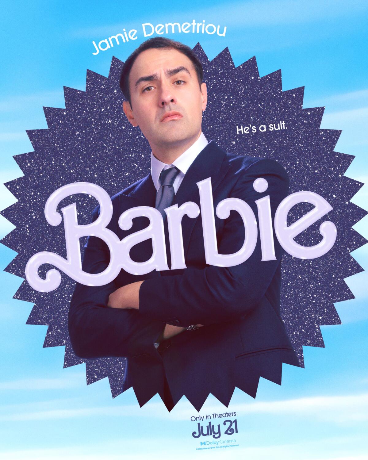 Jamie Demetriou poses with his hands on his hips in a "Barbie" movie poster. He wears a blue suit and tie.