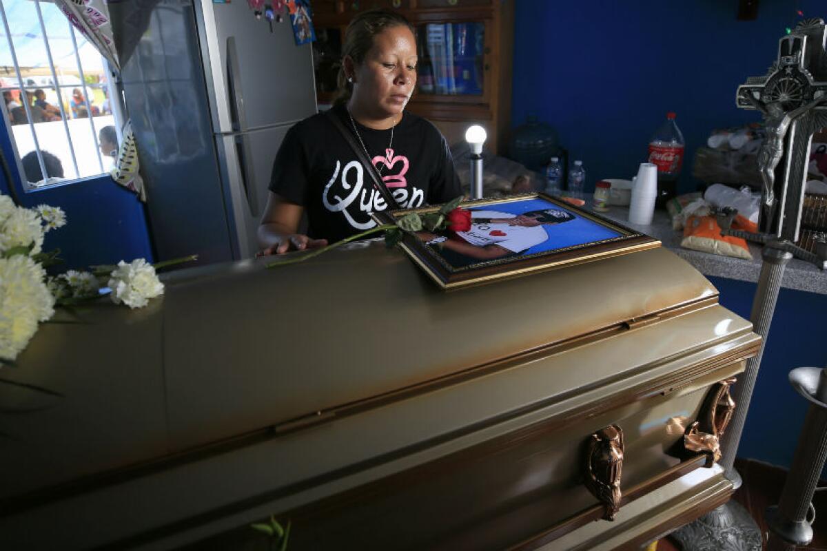 Vanessa Galindo Blas places a rose on the coffin of her common-law husband, Erick Hernandez Enriquez