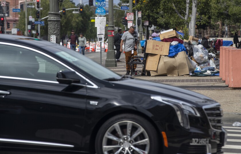 A limousine passes a makeshift shelter of cardboard and plastic.