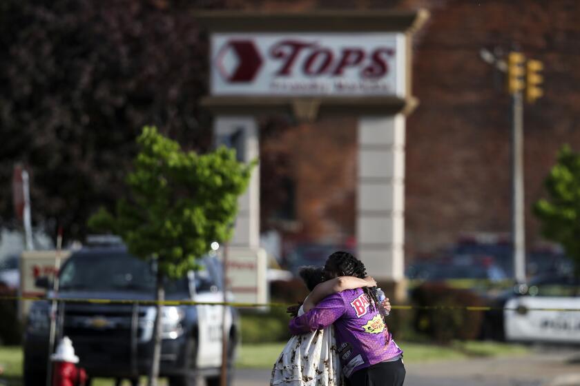 FILE - People hug outside the scene after a shooting at Tops supermarket, May 14, 2022, in Buffalo, N.Y. The city of Buffalo will pause Sunday, May 14, 2023 to mark the passing of one year since a gunman killed 10 people and injured three others in a racist attack that targeted Black people at a city supermarket.(AP Photo/Joshua Bessex, File)