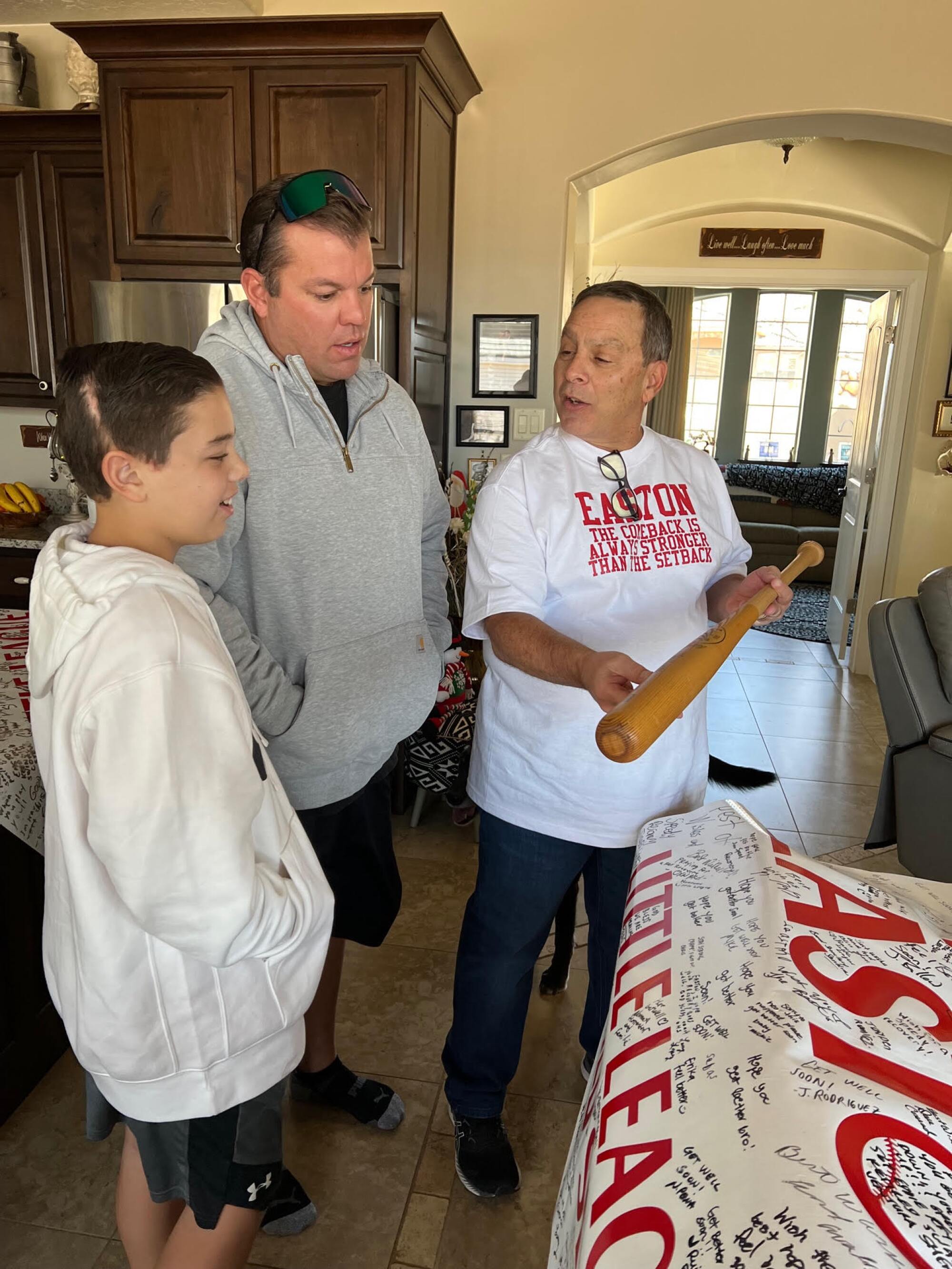 Easton Oliverson, left, and his father, Jace Oliverson, admire the Don Drysdale-signed bat that Frank Randazzo is holding.