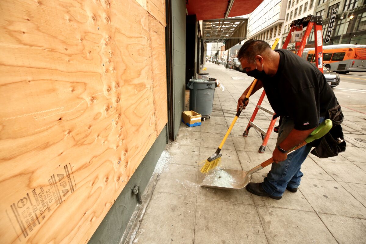 Juan Rodriguez boards up a store on Broadway in downtown L.A. on Tuesday morning after demonstrators vandalized windows.