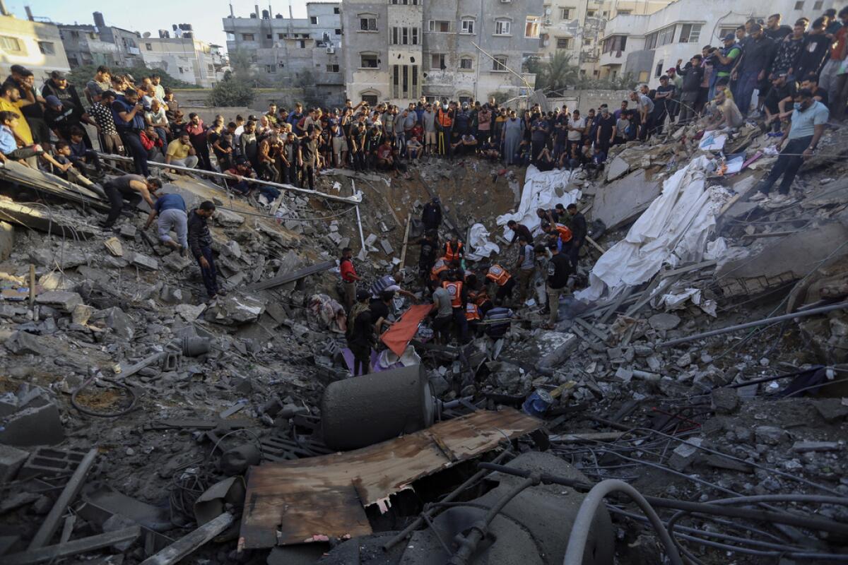 Palestinos reunidos en torno a los restos de una casa