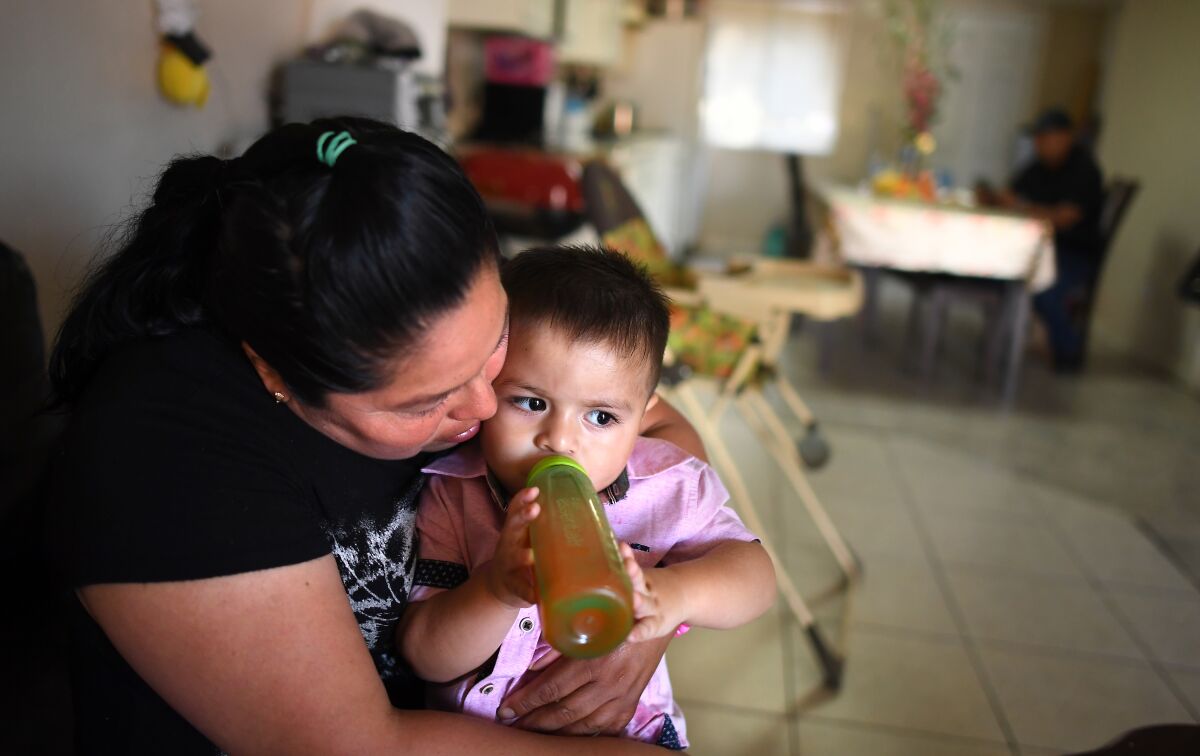 Jose Bello's mother Araceli Reyes holds his 1 year-old son Ethan Bello at his home.