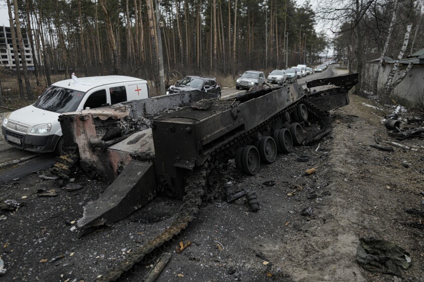 Una fila de vehículos pasa junto a un tanque ruso destruido, en Irpin, Ucrania, el 9 de marzo de 2022.