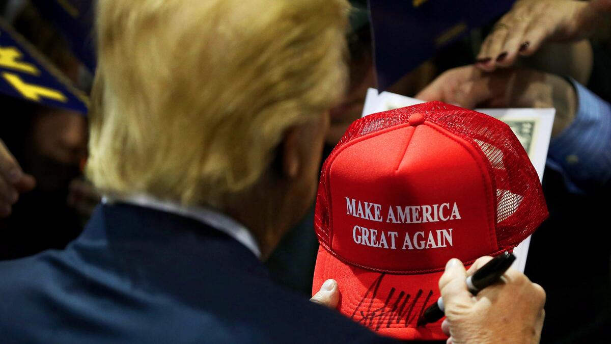 Donald Trump signs one of his iconic campaign hats during an event in Iowa in January.