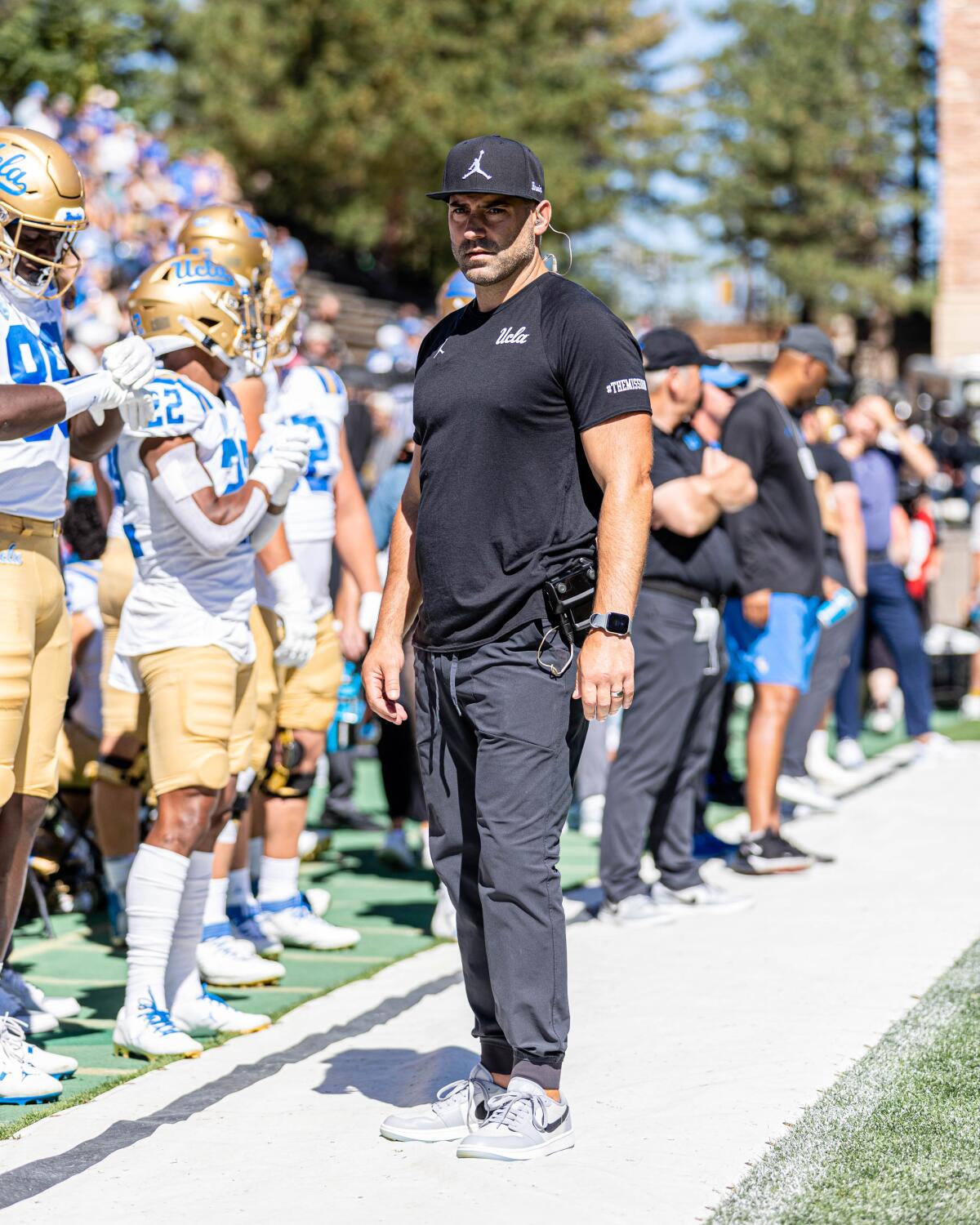 Bryce McDonald, the chief of staff for UCLA football, stands on the sideline.