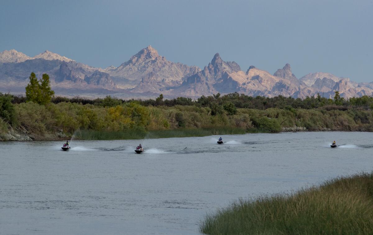Jet skiers on a river next to mountains